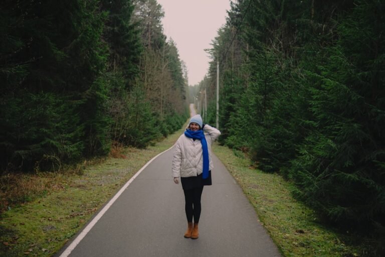 Woman walking on a paved path through a forest.