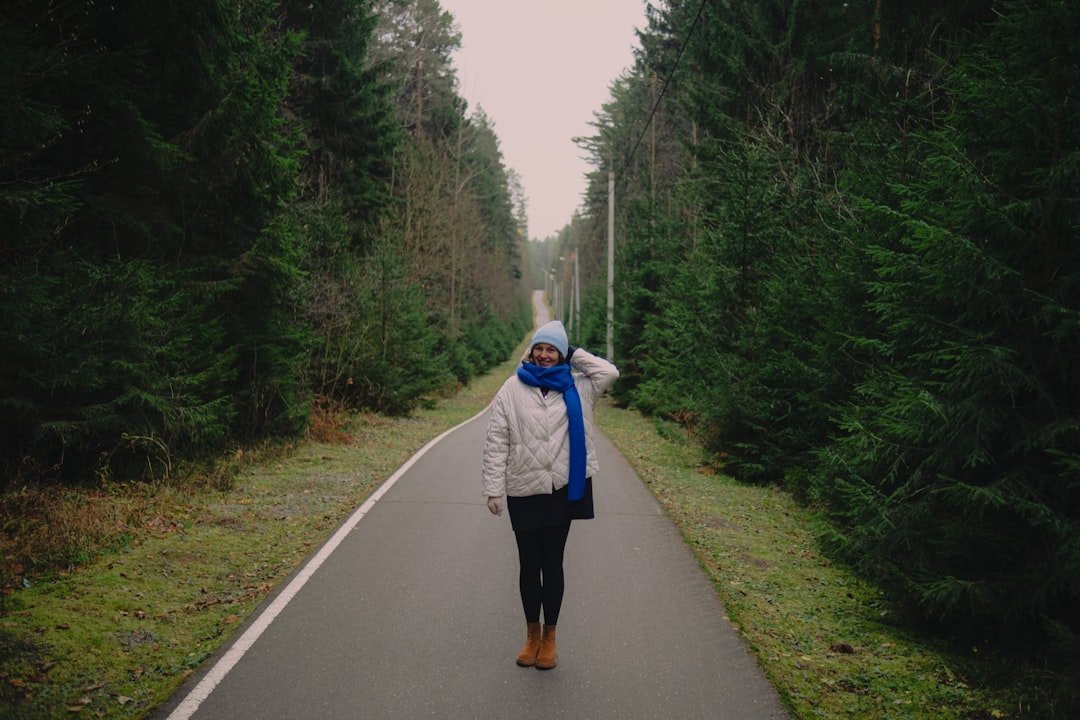 Woman walking on a paved path through a forest.
