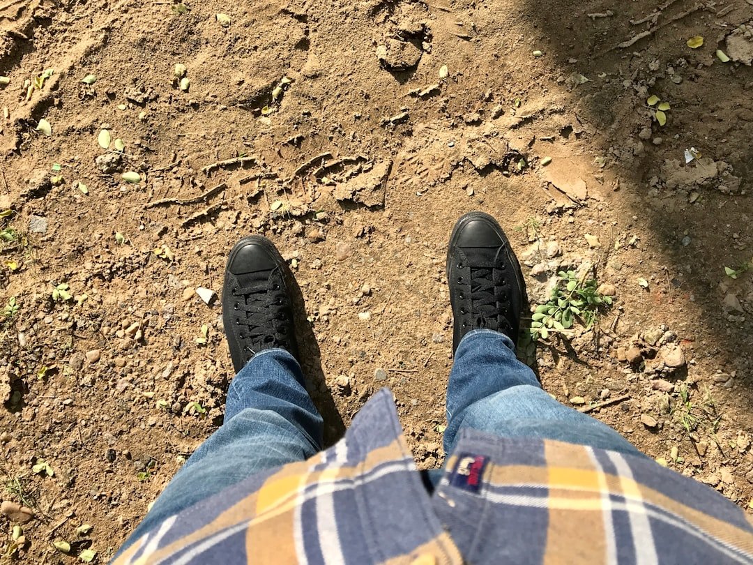 A person standing in the dirt with their feet up