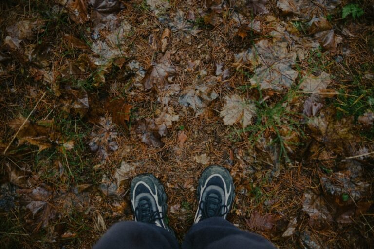 Feet wearing sneakers on a forest floor.